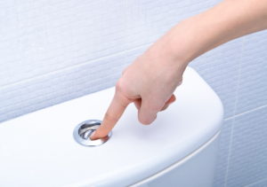 Finger pushing button to flush toilet