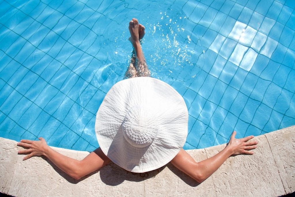 Woman wearing a big hat in a swimming pool