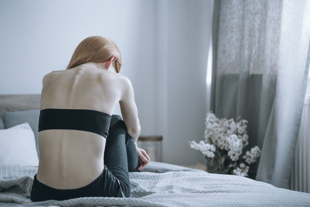 Woman with anorexia sitting on bed